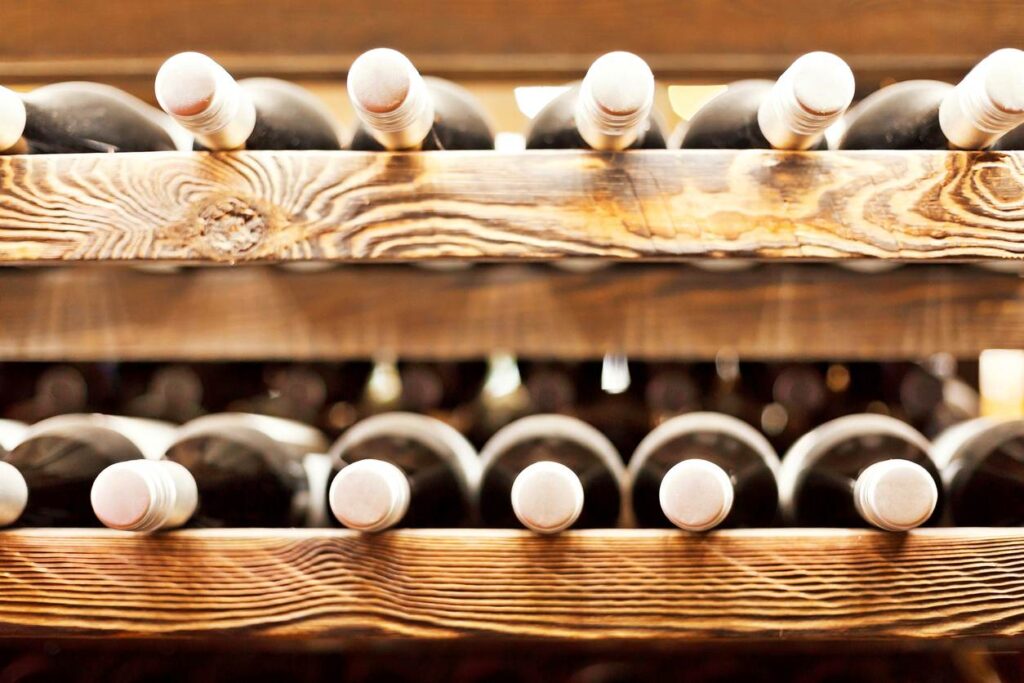Two rows of a wine rack that are lined with sealed bottles.