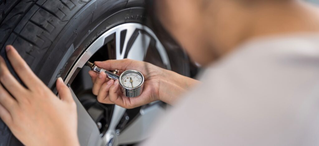 A person uses a tire pressure gauge to see if they need to inflate their tires.