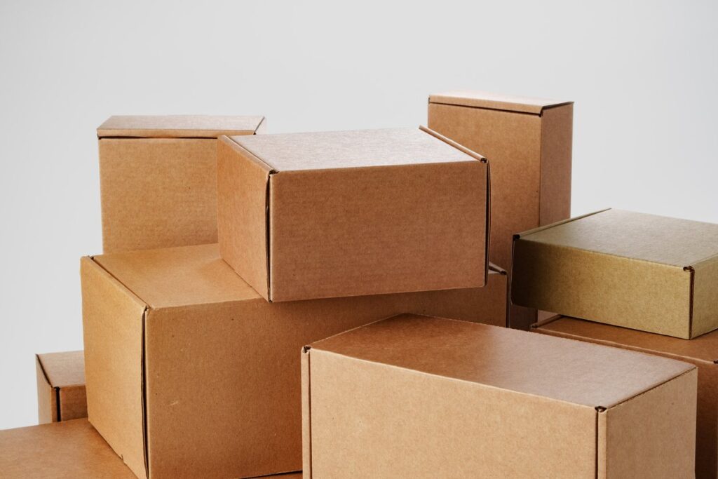 Various small, medium, and large cardboard boxes stack on top of each other in front of a solid-colored background.