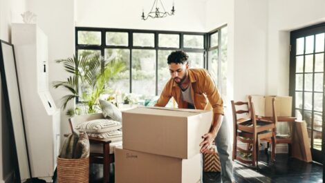 A man carries large cardboard boxes while moving in preparation for storage.